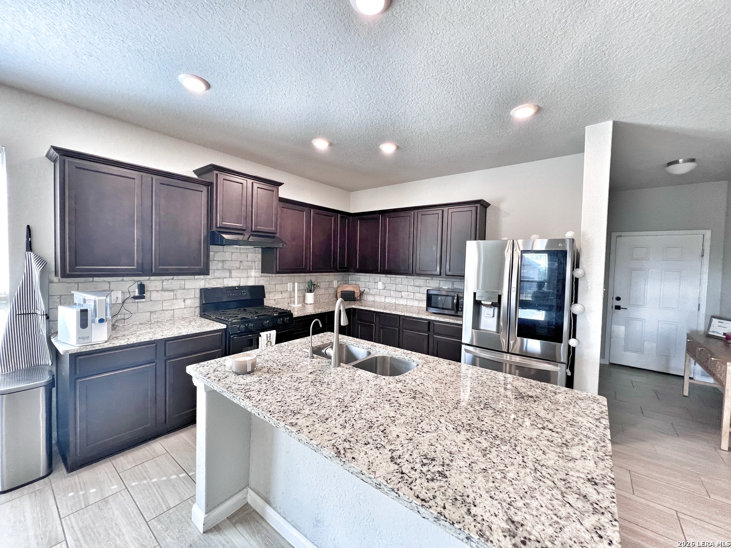 1224 Loma Ranch New Braunfels, TX 78132 - Photo 12 of 29 a kitchen with stainless steel appliances kitchen island granite countertop a sink refrigerator and cabinets