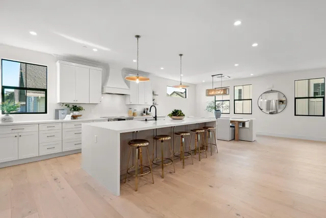 a living room with furniture a mirror and kitchen view