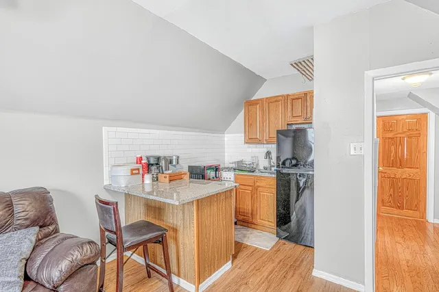 a kitchen with stainless steel appliances kitchen island granite countertop a refrigerator a stove a sink dishwasher and white cabinets with wooden floor