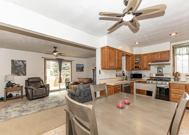 a kitchen with a stove a sink dishwasher a dining table and chairs with wooden floor