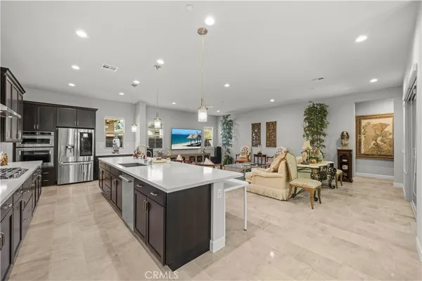 a large kitchen with kitchen island a sink a counter top space and a view of living room