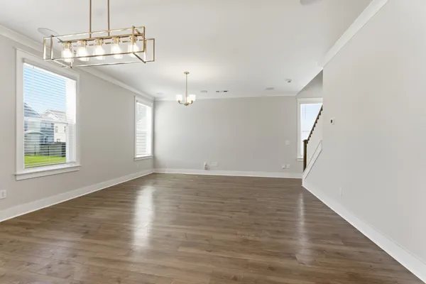 an empty room with wooden floor chandelier and windows