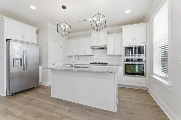 a kitchen with stainless steel appliances granite countertop a sink a stove and refrigerator