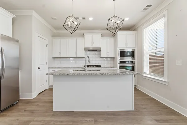 a kitchen with kitchen island granite countertop a sink a counter space stainless steel appliances and cabinets