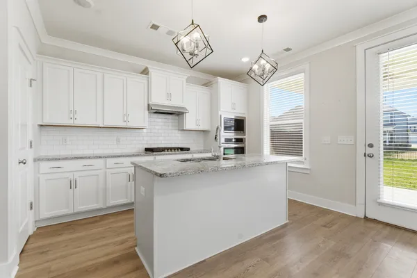a kitchen with cabinets wooden floor and a window