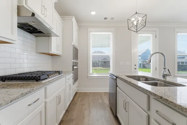 a kitchen with granite countertop a sink stove and cabinets