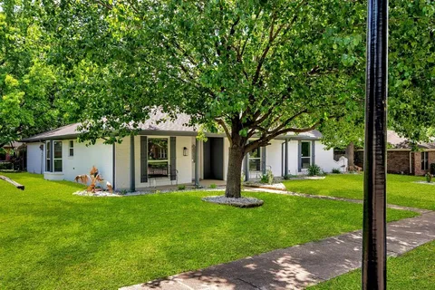 a front view of house with a garden and trees