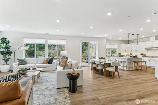 a living room with lots of furniture wooden floor and a large window