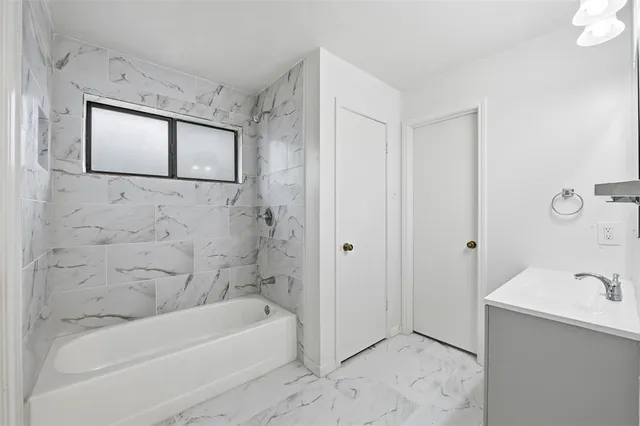 a bathroom with a tub a sink and mirror
