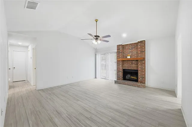 a view of an empty room with a fireplace and a window