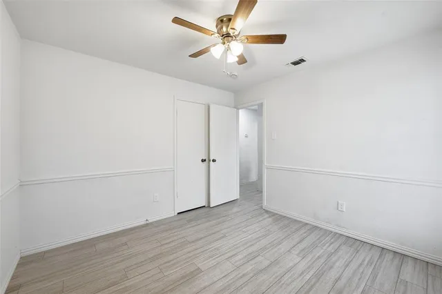 an empty room with wooden floor and fan
