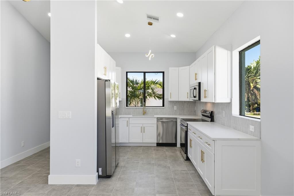 19871 Adams Road Fort Myers, FL 33908 - Photo 11 of 25 Kitchen with stainless steel appliances, white cabinets, decorative light fixtures, light stone countertops, and recessed lighting