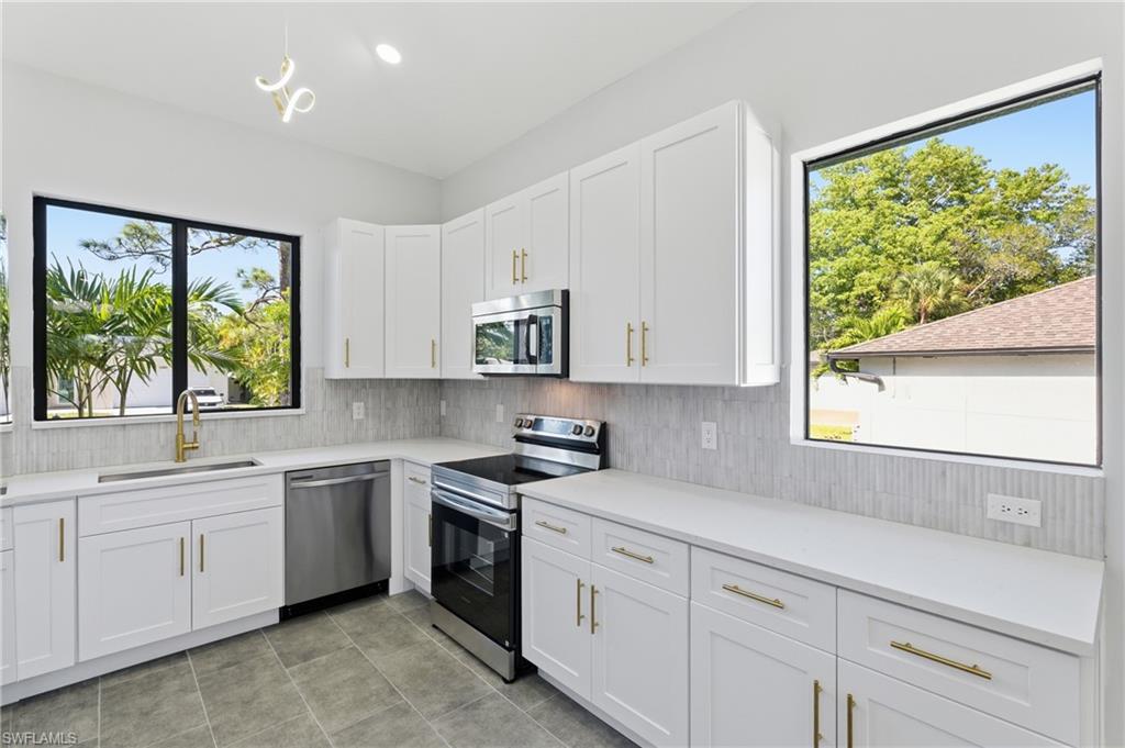 19871 Adams Road Fort Myers, FL 33908 - Photo 7 of 25 Kitchen with appliances with stainless steel finishes, white cabinets, light stone counters, recessed lighting, and decorative backsplash
