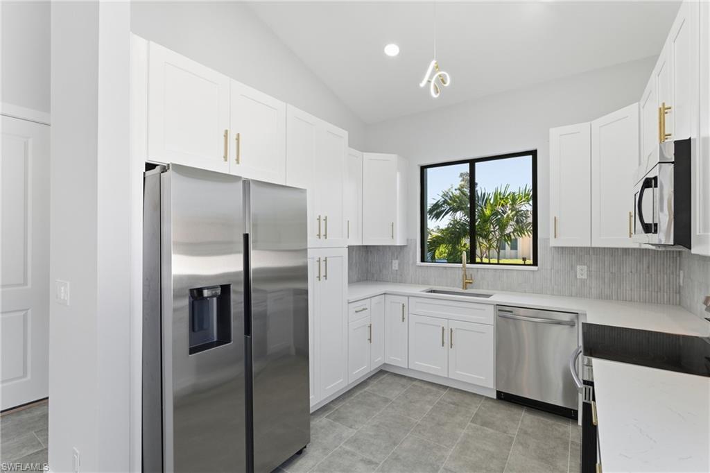 19871 Adams Road Fort Myers, FL 33908 - Photo 8 of 25 Kitchen with appliances with stainless steel finishes, white cabinets, lofted ceiling, light stone counters, and recessed lighting