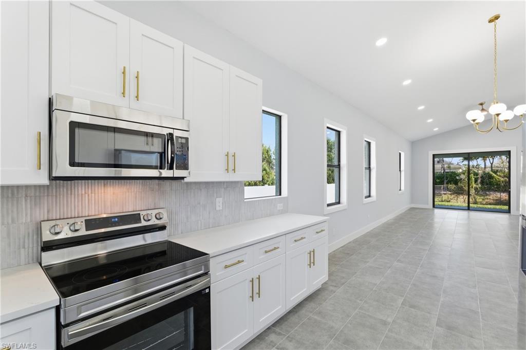 19871 Adams Road Fort Myers, FL 33908 - Photo 9 of 25 Kitchen featuring appliances with stainless steel finishes, recessed lighting, vaulted ceiling, white cabinets, and pendant lighting