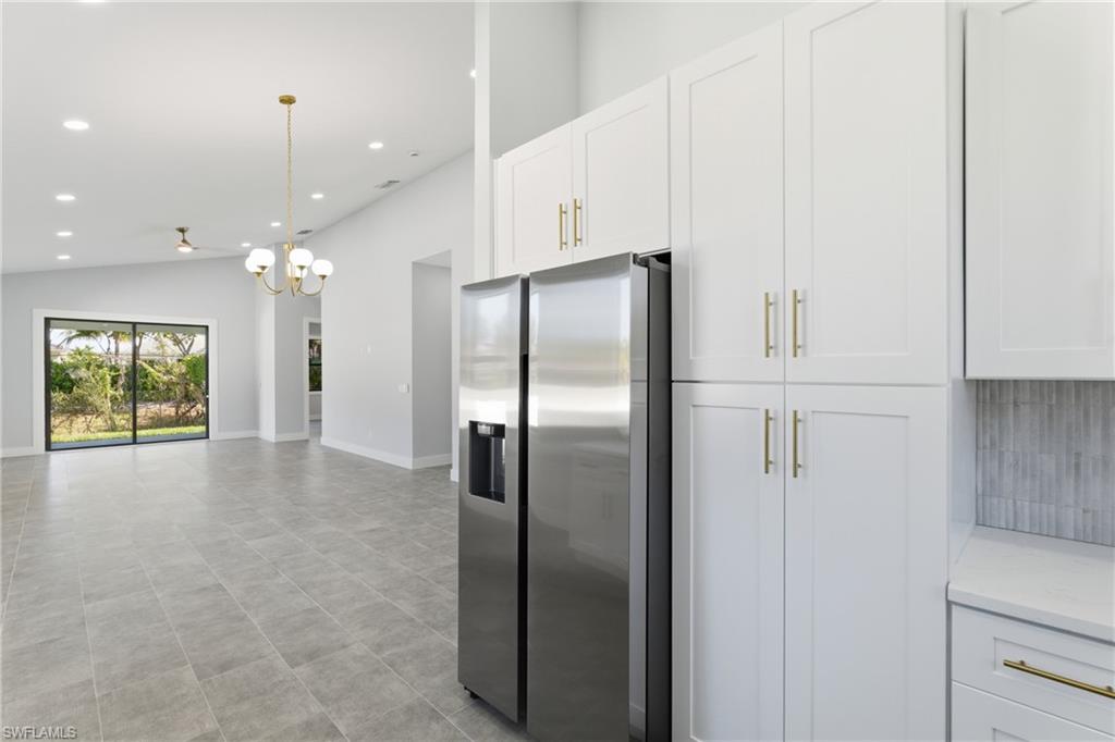 19871 Adams Road Fort Myers, FL 33908 - Photo 10 of 25 Kitchen with white cabinets, stainless steel fridge, a chandelier, recessed lighting, and hanging light fixtures