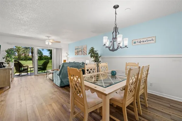 a dining room with furniture a chandelier and wooden floor