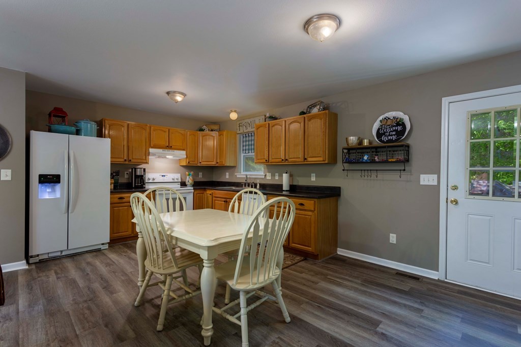 142 Cedar Heights Road Spring City, TN 37381 - Photo 8 of 25 a kitchen with granite countertop a refrigerator a stove a sink and a dining table with wooden floor