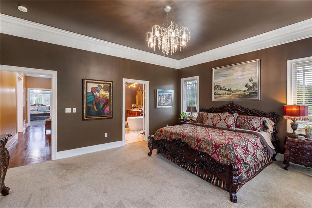 265 Honeysuckle Lane Temple, GA 30179 - Photo 19 of 45 a spacious bedroom with a large bed and a chandelier