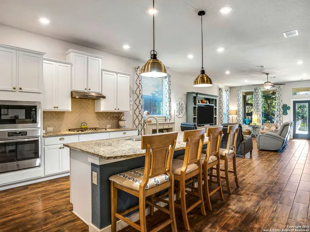 a open kitchen view with stainless steel appliances granite countertop a stove a sink a oven a dining table and chairs