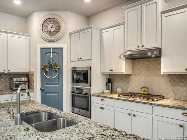 a kitchen with stainless steel appliances granite countertop a sink a stove and cabinets