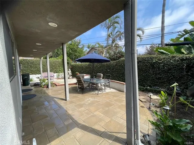 a view of a patio with a table and chairs under an umbrella with a garden