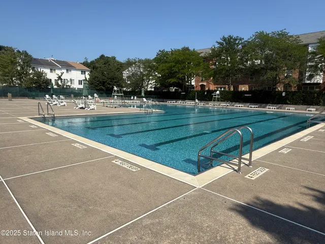 a view of swimming pool with seating space and trees in the background