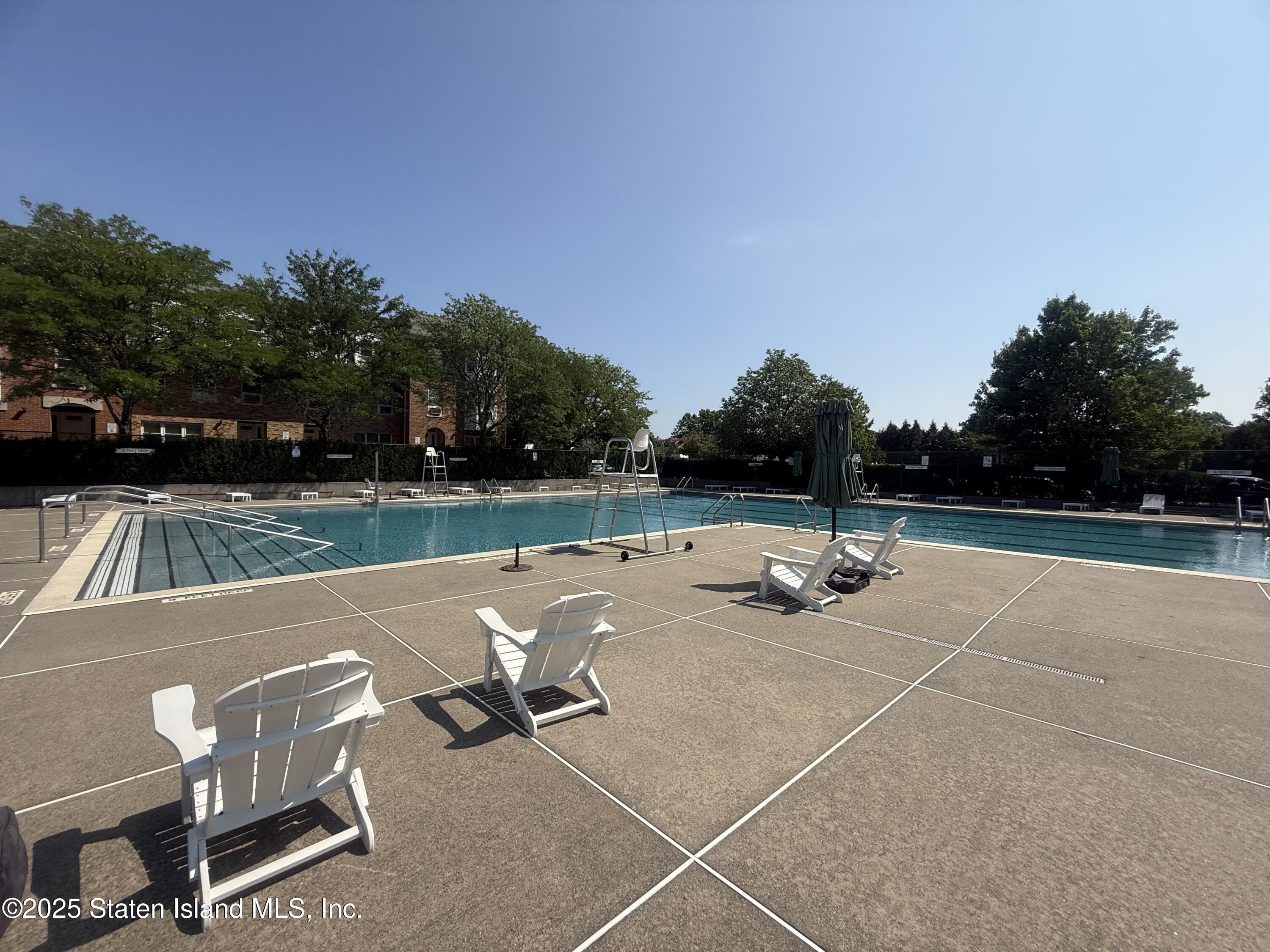 214 Ilyssa Way Staten Island, NY 10312 - Photo 15 of 22 a view of swimming pool with seating space and trees in the background