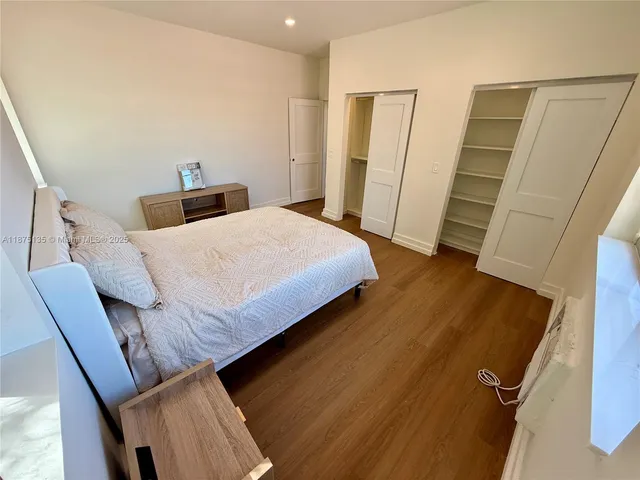 a bedroom with a bed and a dresser with wooden floor