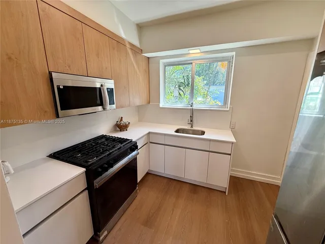 a kitchen with stainless steel appliances a refrigerator sink and wooden floor