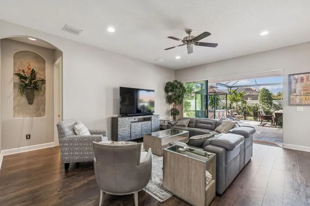 a living room with lots of furniture wooden floor and a large window