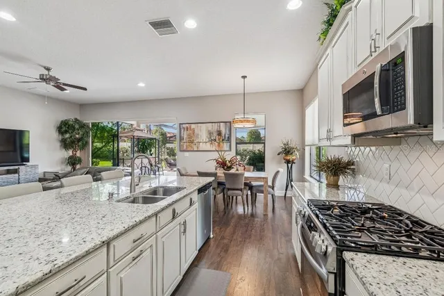 a kitchen with stainless steel appliances granite countertop a stove top oven a refrigerator a sink and white cabinets