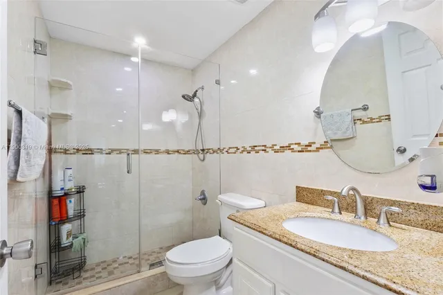 a bathroom with a granite countertop sink a toilet and a mirror
