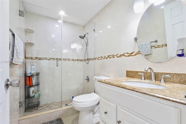 a bathroom with a granite countertop sink a toilet and shower