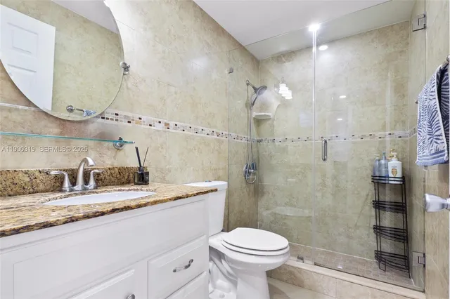 a bathroom with a granite countertop sink mirror toilet and shower