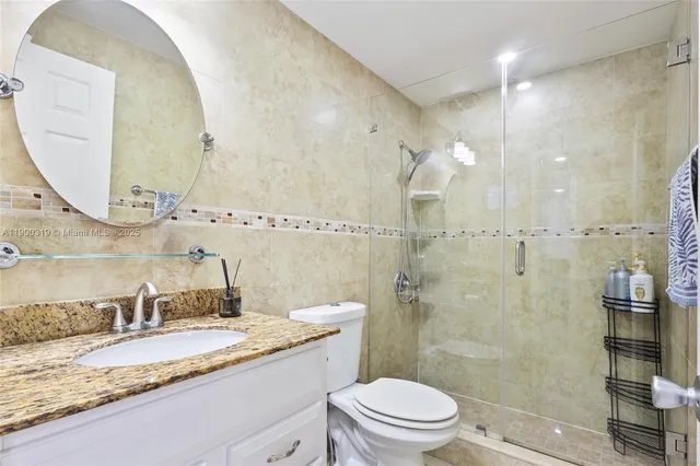a bathroom with a granite countertop sink a mirror and a toilet