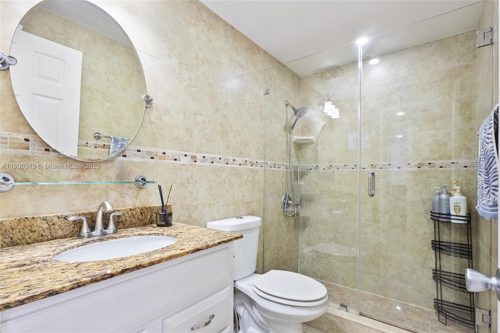 5665 West 20th Avenue, Unit 212 Hialeah, FL 33012 - Photo 20 of 38 a bathroom with a granite countertop sink a mirror and a toilet