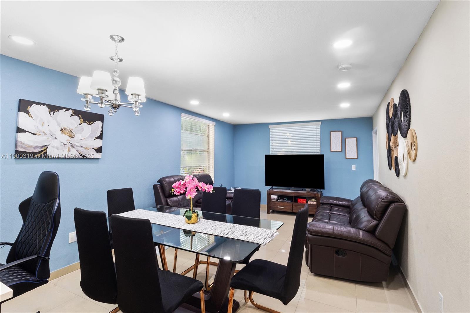 5665 West 20th Avenue, Unit 212 Hialeah, FL 33012 - Photo 5 of 38 a living room with furniture flat screen tv and a chandelier