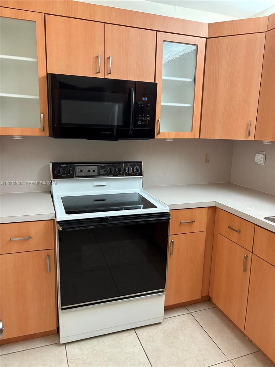 8335 Southwest 72nd Avenue, Unit 108D Miami, FL 33143 - Photo 5 of 20 a kitchen with granite countertop a stove and a microwave