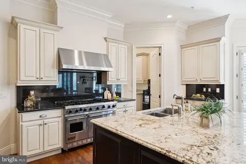 a kitchen with granite countertop a stove a sink and a wooden cabinets