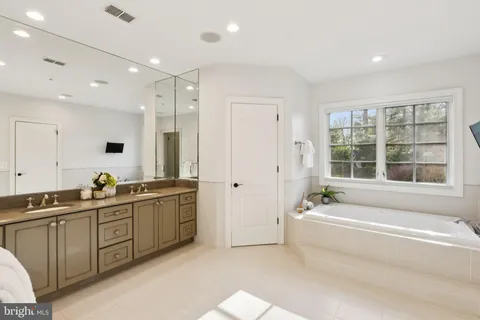 a spacious bathroom with a double vanity sink a large mirror and a bathtub