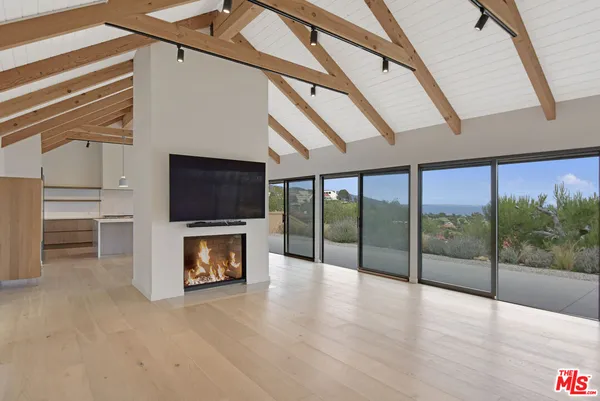 a large kitchen with stainless steel appliances a large counter top a refrigerator and cabinets