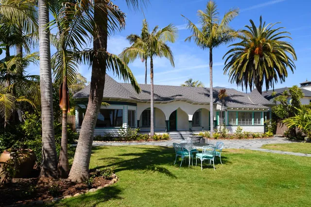 a front view of a building with garden and trees