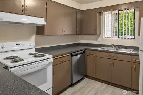 a kitchen with a stove white cabinetry and large windows
