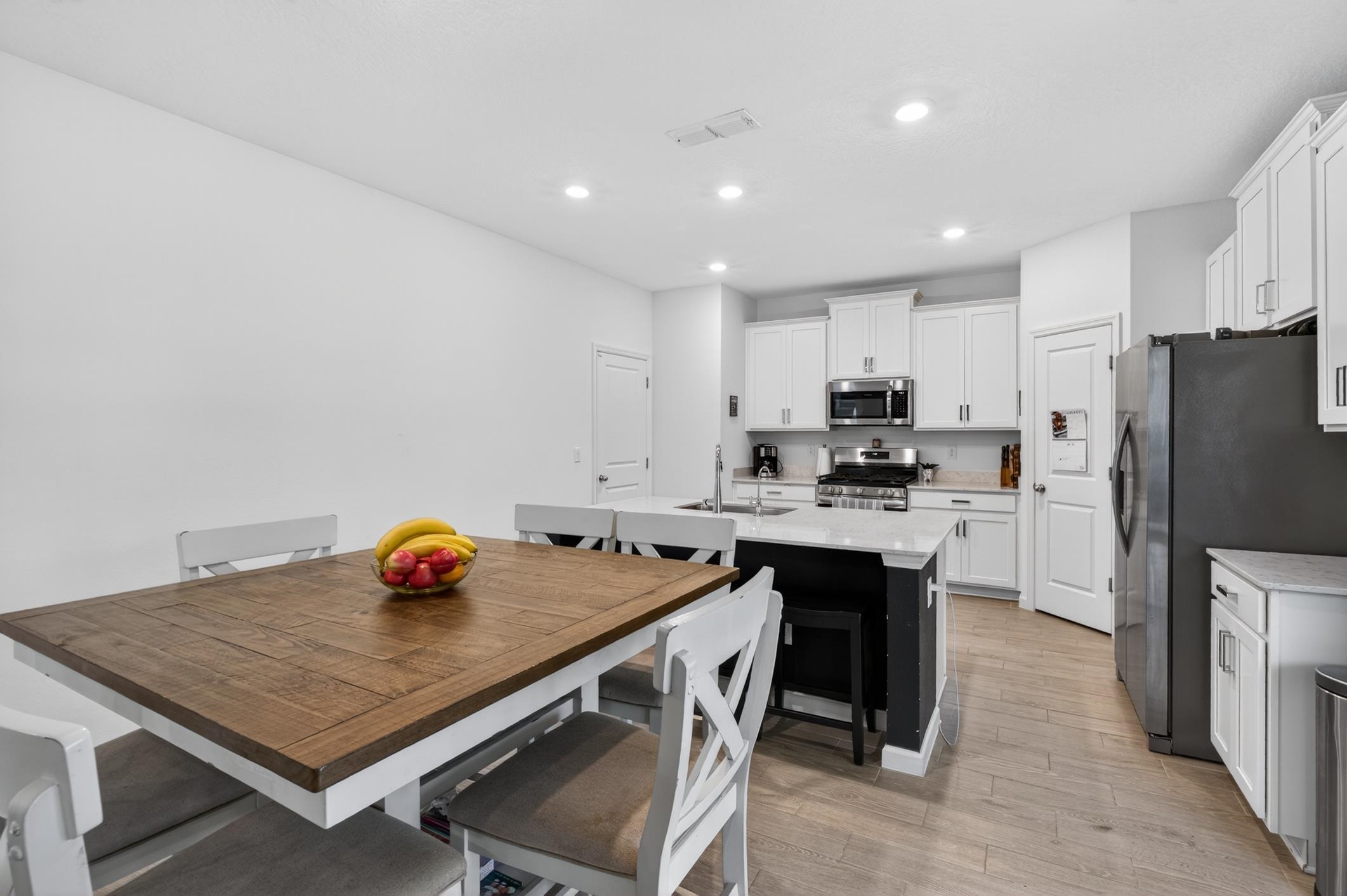 177 White Rabbit Run St. Augustine, FL 32092 - Photo 15 of 51 Kitchen with stainless steel appliances, white cabinetry, a kitchen breakfast bar, an island with sink, and light stone counters