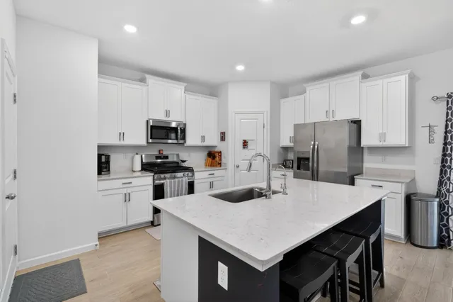 a kitchen with a refrigerator a stove a sink a dining table and chairs