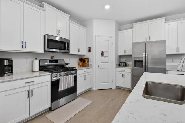 a kitchen with white cabinets and stainless steel appliances