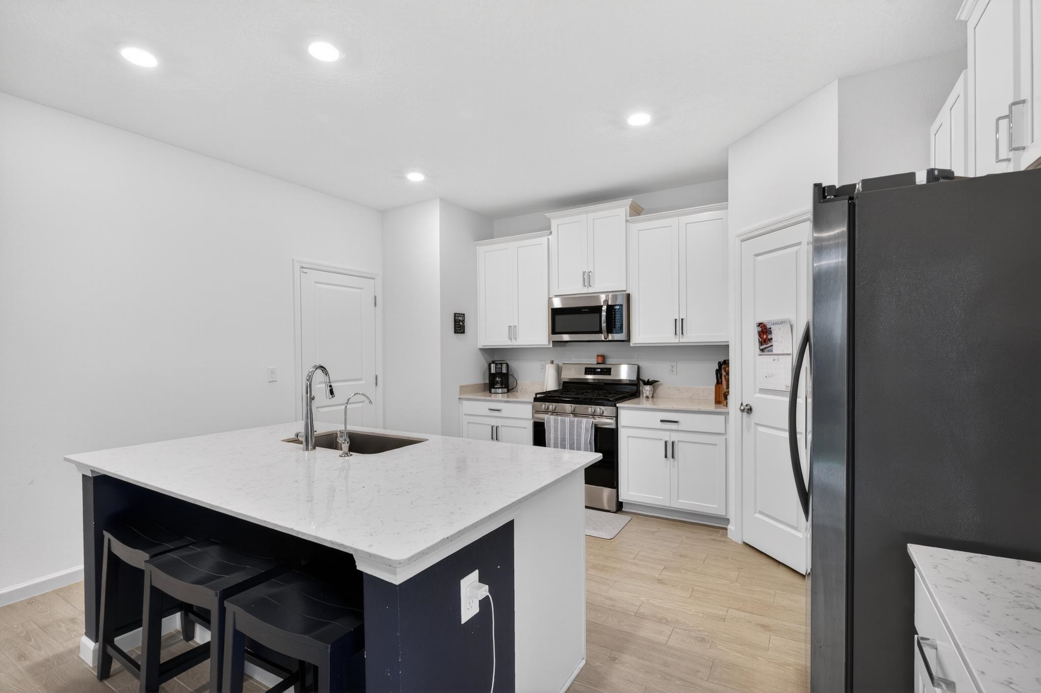177 White Rabbit Run St. Augustine, FL 32092 - Photo 21 of 53 Kitchen with stainless steel appliances, a kitchen bar, a center island with sink, light wood-style floors, and light stone countertops
