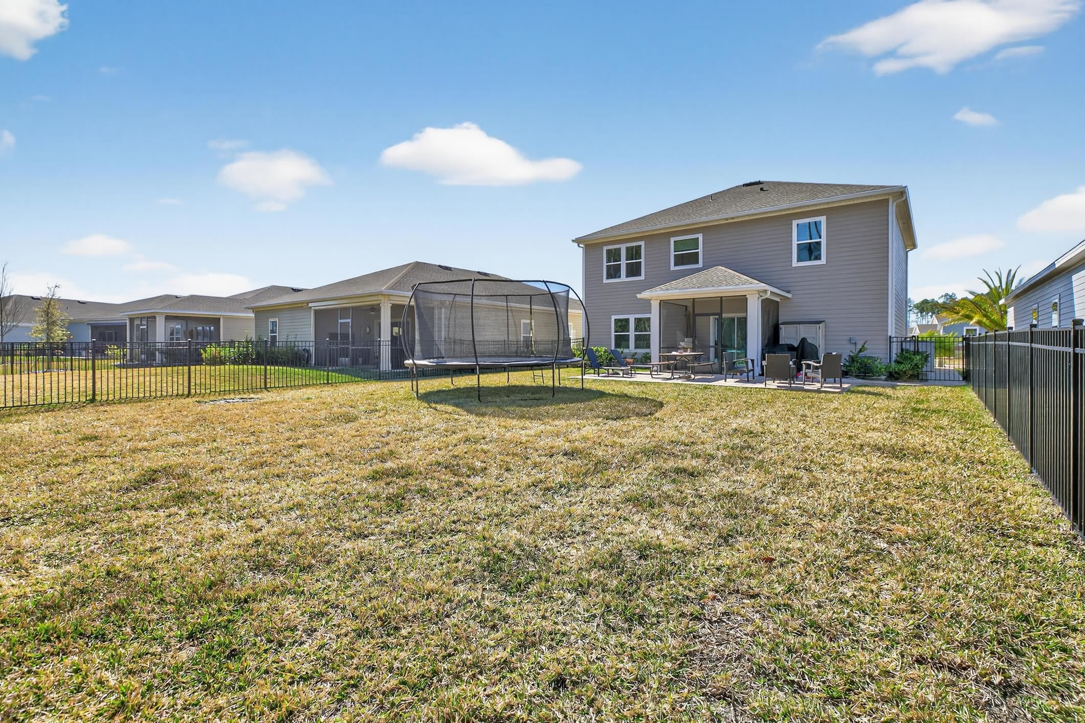 177 White Rabbit Run St. Augustine, FL 32092 - Photo 46 of 51 Rear view of property featuring a trampoline, a fenced backyard, a patio area, and a sunroom
