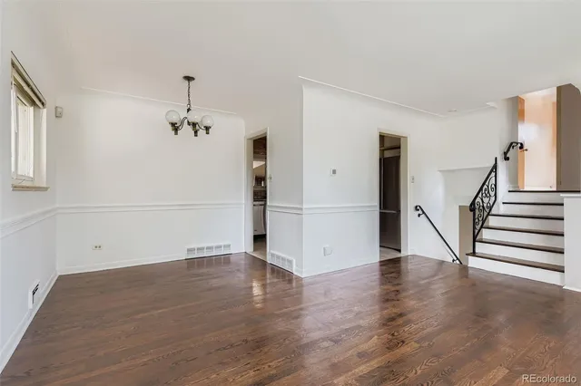 a view of an empty room with wooden floor and stairs